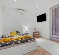 Bedroom in a family house with a bed, TV, and floor with wooden decor.