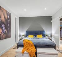 Bedroom in a family house with a bed, colorful pillows, and an open wardrobe.