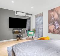 Bedroom with a TV, air conditioning, an armchair, and decorative art in a family house.