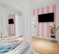 Bedroom in a family house with a striped wall, television, and wood-patterned flooring.