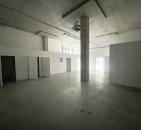 Open space with concrete flooring in commercial premises, white walls and a pillar.