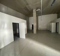 Interior of commercial premises with concrete flooring and multiple doors.