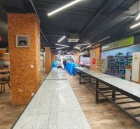 Gastro premises with wooden decor flooring, tables, and food in the background.