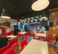 Gastro premises with wooden decor flooring, red chairs, and lights.