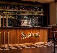 Bar counter with beer taps and decorative lighting in a gastro space with a wooden decor floor.
