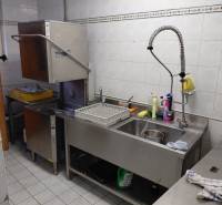 Kitchen washing areas with an industrial dishwasher and stainless steel sink in gastro spaces.