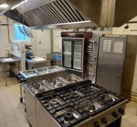 A kitchen in a gastro space with a stove, sink, and refrigeration equipment.