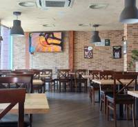 Interior of a gastro space with brick walls, a wooden decor floor, and hanging lamps.