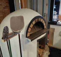 Pizza oven and tools in a gastro space with firewood and a brick wall.