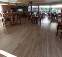 Interior of dining spaces with striped chairs and a wooden-patterned floor.