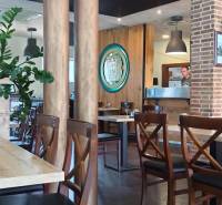 A restaurant with wooden decor and a brick fireplace in the dining area.