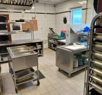 Kitchen gastro spaces with stainless steel equipment and white tiles on the walls.