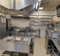 A kitchen space in a gastro facility with stainless steel equipment and white tiles.