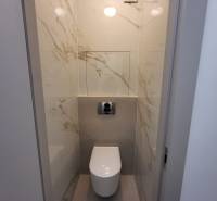 A toilet with marble-patterned tiles in a 2-room apartment.