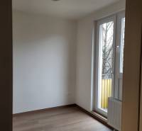 A room in a 2-bedroom apartment, floor with wood decor, large window to the balcony.