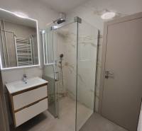 Bathroom with a spacious shower and a sink in a 2-room apartment.