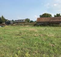 Plots - housing on Poľnohospodárska Street in Trenčín with a grassy area and a farm building.