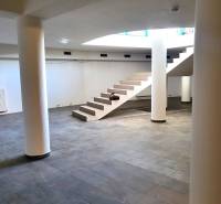 Commercial spaces with marble flooring and staircase, supported by columns.