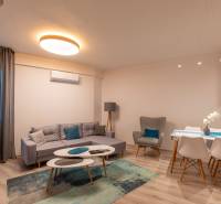 Living room in a two-room apartment with a wooden decor floor, a sofa, and a dining table.