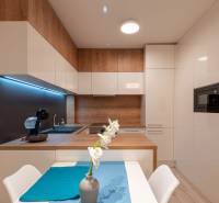 A kitchen in a 2-room apartment with light furniture and a wooden decor floor.
