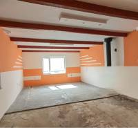 Interior of a family house with exposed wooden beams and light orange walls.