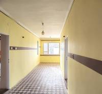 A hallway in a family house with a tiled floor and yellow walls.