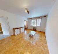 Living room in a three-room apartment with a wooden decor floor and a glass table.