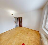 A room with a wooden floor decor, white walls, and a large window in a 3-room apartment.