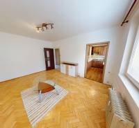 Living room with wood-patterned flooring and a glass table in a three-room apartment.