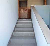 A staircase with ceramic tiles leads to an entrance secured by a wooden gate.