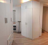 White cabinets in a studio apartment with a wood-patterned floor, room illuminated by a lamp.