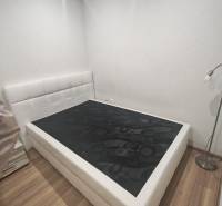 Bedroom with a bed, nightstand, and wooden decor flooring in a studio apartment.