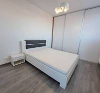 Bedroom with a large bed, nightstand, and sliding wardrobe in a 2-room apartment.