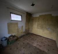 The interior of a cabin with raw walls and floor; building materials in the corner.