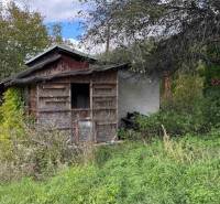 An abandoned cottage in Hlohovec surrounded by dense vegetation and neglected surroundings.