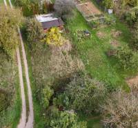 A cottage in Hlohovec surrounded by greenery and a garden, with a visible access road.