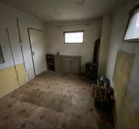 A room in a cottage with wooden decor and a tiled stove.