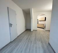 A studio apartment with a wooden decor floor and a kitchen area.