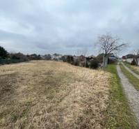 Land for sale on Ladislava Novomeského Street in Hlohovec, surrounded by family houses.