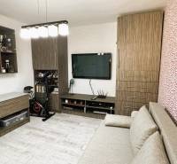A room in a 3-room apartment with a television, a sofa, and a wooden decor floor.