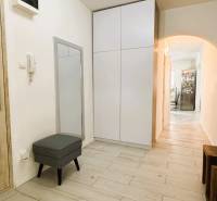 A hallway of a 3-room apartment with a wooden decor floor, a mirror, and storage space.