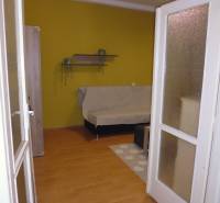 Interior in a 1-room apartment with a wood-patterned floor and a yellow wall.