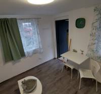 A cottage with a wooden floor decor, curtains, a table, and two white chairs.
