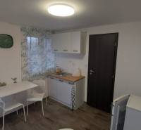 A cottage with a kitchenette, a table, white cabinets, and a floor with a wood decor.