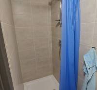 Shower stall with a blue curtain and tiles in a cabin.