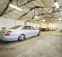 Interior of commercial space with a car, exposed ceiling, tables, and chairs.