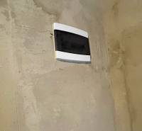 An electrical distribution box on a peeling wall in the interior of a cottage.