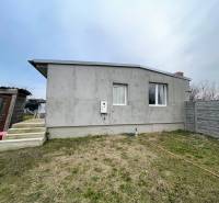 A cottage in Komárno with a concrete facade, stairs, and a fenced plot.