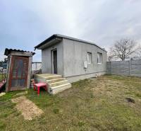 A house in Komárno with a concrete facade, a staircase, and a garden surrounded by a fence.