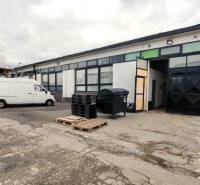 A building of warehouses and halls with cars in Trenčín, highlighted company advertisement in the foreground.